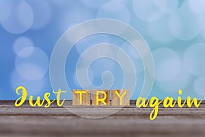 Inspirational quote - Just try again. Motivational words with wooden block concept on vintage soft blue bokeh background