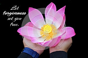 Inspirational quote - Let forgiveness set you free. With woman holding a pink lotus flower blossom in hands on black background.