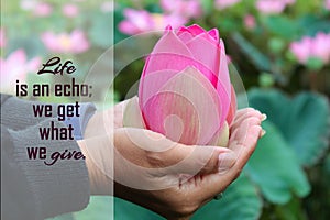 Inspirational quote - Life is an echo. We get what we give. With person holding red pink lotus flower or Nelumbo nucifera in hands