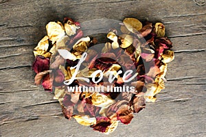 Inspirational quote - Love without limits. With heart made of dried roses petals on wooden table background.