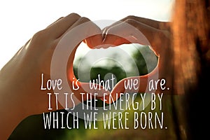 Inspirational quote - Love is what we are. It is the energy by which we were born.  With young woman making hands love sign. photo