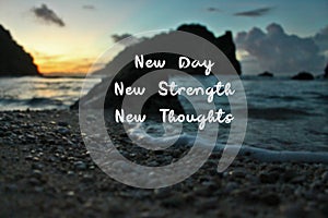 Inspirational quote - New Day. New Strength. New Thoughts. On Blurry background of morning light over the beach at sunrise.