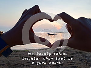 Inspirational quote - No beauty shines brighter than that of a good heart. With blurry hands love sign focus on fishing boat