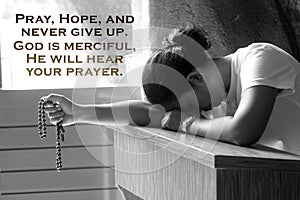 Inspirational quote - Pray, hope, and never give up. God is merciful. He will hear your prayer. With tiring woman holding rosary. photo