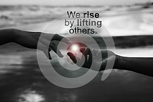 Inspirational quote - We rise by lifting others. With helping hands touch the light, reaching out each other. Humanity concept. photo