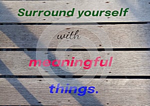 Inspirational quote - Surround yourself with meaningful things. A sign on a rustic wooden wall with colorful text message.