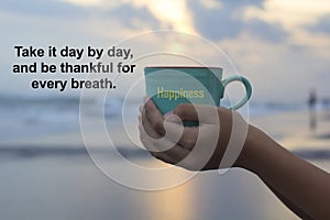 Inspirational quote - Take it day by day, and thankful for every breath. With person holding a cup of coffee in hands.