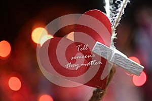 Inspirational quote  - Tell someone they matter. Motivational message on background of red heart on a string.