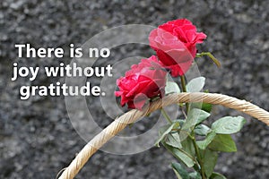 Inspirational quote - There is no joy without gratitude. With bouquet of red roses on in wooden basket on black background.