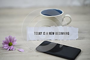 Inspirational quote - Today is a new beginning. With morning a cup of coffee, black smartphone and purple daisy flower .