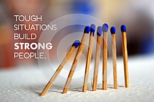 Inspirational quote - Tough situations build strong people. On background of  blue wooden matches standing as an illustration.