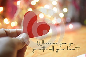 Inspirational quote - Wherever you go, go with all your heart. On pink and white bokeh light background with hand holding red love photo
