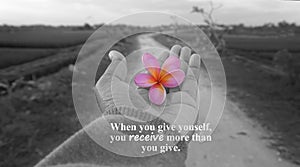 Inspirational quote - When you give yourself, you receive more than you give. With one human hand and rural scenery background in