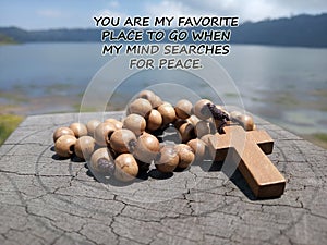 Inspirational quote - You are my favorite place to go when my mind searches for peace. With blue lake background & wooden rosary