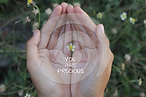 Inspirational quote - You are precious. With beautiful tiny flower in hand. Self love and care concept.