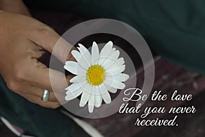 Inspirational words - Be the love that you never received. Giving kindness motivational quote concept with person holding a flower