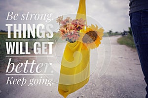 Inspirational words - Be strong. Things will get better. Keep going. Young man or woman with bouquet of flowers in yellow eco bag.