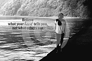 Inspirational words - Believe what your heart tells you, not what others say. With young girl walking alone in the lake.
