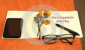 Inspirational words - Focus on being productive instead of busy. Notes on a notebook concept with dried roses flowers.