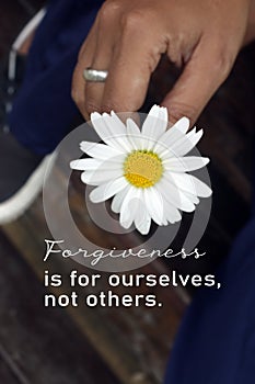 Inspirational words - Forgiveness is for ourselves, not others. Forgive forgiving quotes concept with person holding white flower.