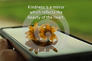Inspirational words - Kindness is a mirror which reflects the beauty of the heart. With two daisy flowers on device surface. photo