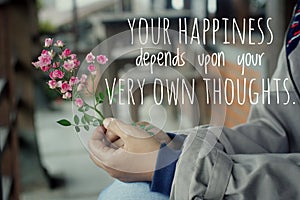 Inspirational words - Your happiness depends upon your very own thoughts. Hands holding pink little roses plant.