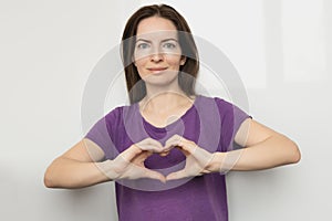 Inspire inclusion. Woman holding her hands in the shape of a heart and holding them in front of her, dressed purple