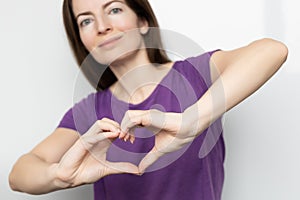 Inspire inclusion. Woman holding her hands in the shape of a heart and holding them in front of her, dressed purple