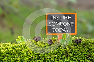 Inspire someone today text on small blackboard