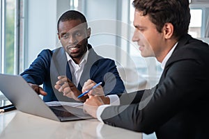 Inspired African American businessman wearing formal suit talking to colleague