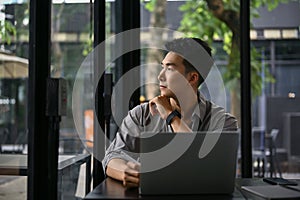 Inspired Asian businessman thinking and daydreaming while looking out the window