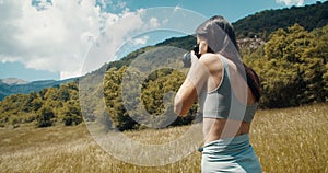 Inspired attractive woman shoot photo on journey to mountain standing on meadow