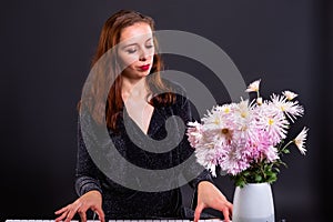 Inspired by autumn flowers, woman composes music on an electronic piano photo