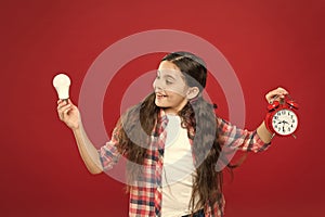 Inspired child hold clock red background. Inspiration and brainstorming. Electricity energy. Little girl hold light bulb