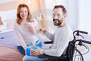 Inspired crippled man smiling and opening a gift