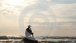 Inspired man on rock in the stormy sea writing the book - dolly shot