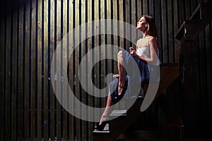 Inspired woman with naked lean legs posing on wooden stairs in d