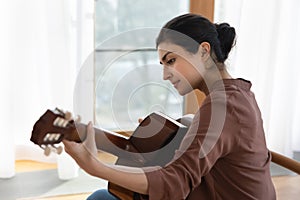Inspired young indian female guitarist hold guitar play lyrical melody