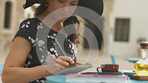 Inspired young lady writing notes in notepad, enjoying hobby in street cafe