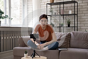 Inspired young woman sit on sofa talk before cellphone webcam