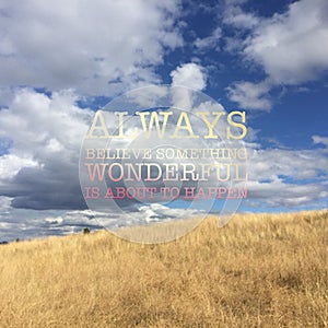 Inspiring colourful text on landscape image of grass field with white clouds and blue sky
