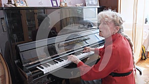Inspirited senior woman plays piano music in light room