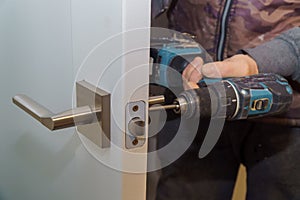 Install the door handle with a lock, Carpenter tighten the screw, using an electric drill screwdriver