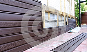 Installation of brown plastic siding on the facade