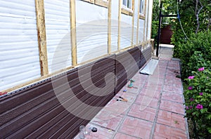 Installation of brown plastic siding on the facade