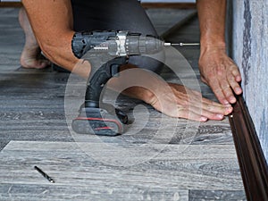 installation of a brown wooden baseboard in a room with a gray interior