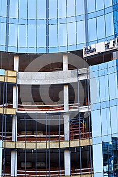 Installation of continuous glazing of the facade of a building under construction with blue glass