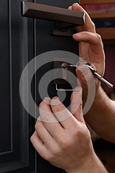 Installation of a door lock, a carpenter installs a door lock in a door, work close-up.