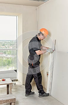 Installation of drywall. The worker is cutting plasterboard