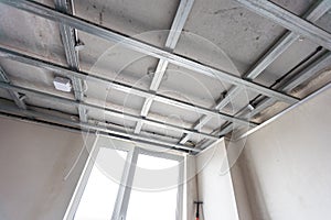 Installation of drywall. Workers are using screws and a screwdriver to attach plasterboard to the ceiling